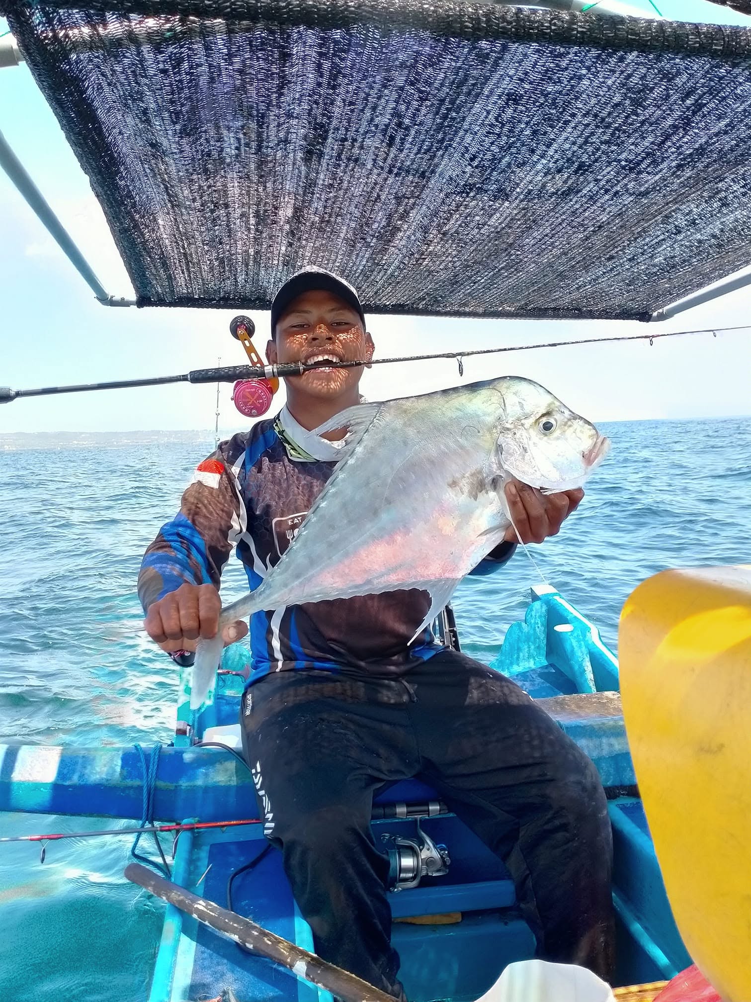 Angler holding a large trevally on board